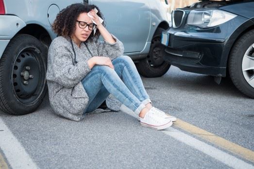 girl with head injury leaning against car after crash