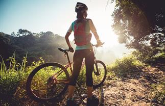 a woman holding her bike on a trail