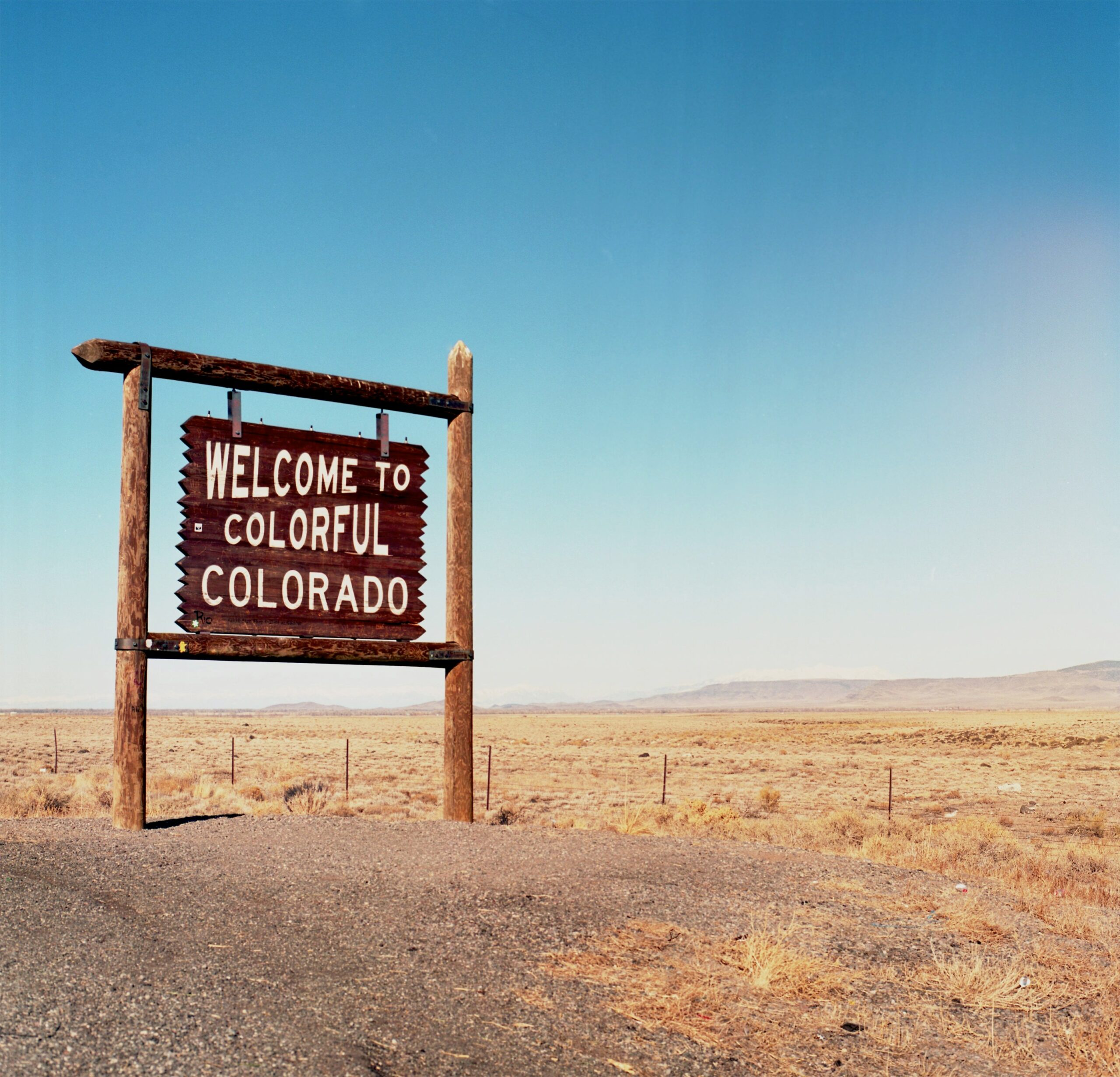 "Welcome to Colorful Colorado" sign in front of a blue sky.