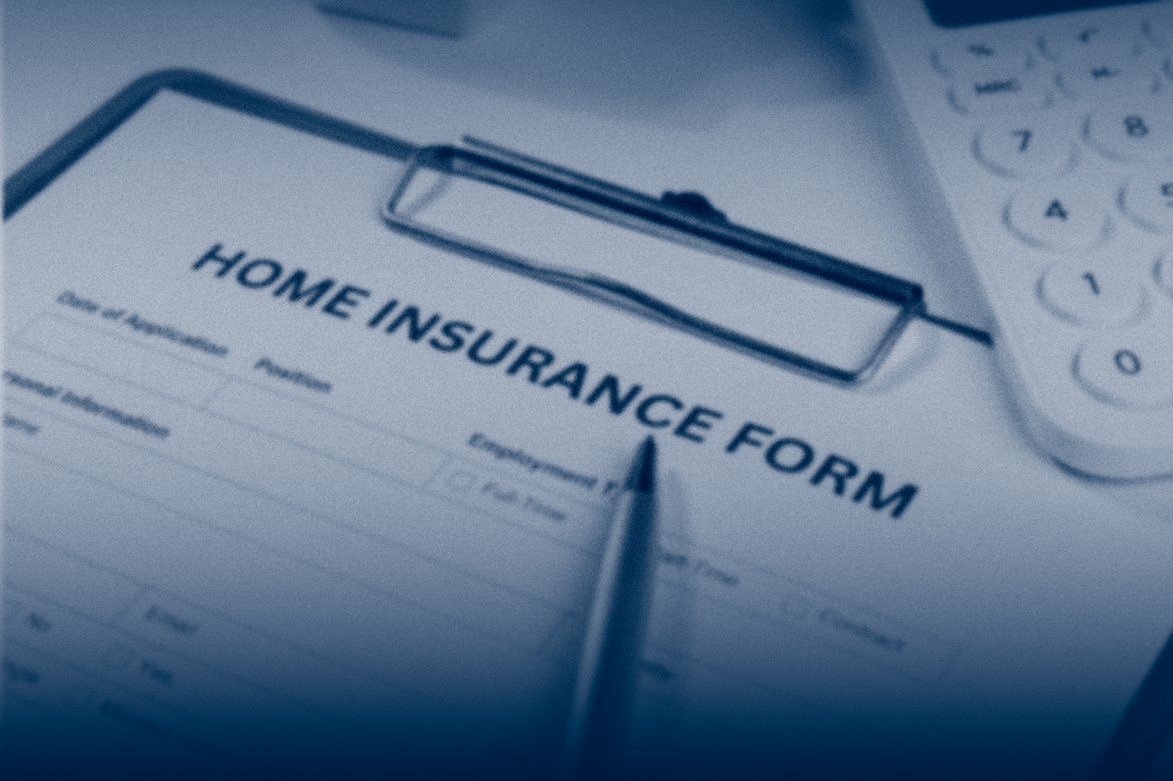 A close-up of a home insurance form on a clipboard with a pen and calculator nearby.