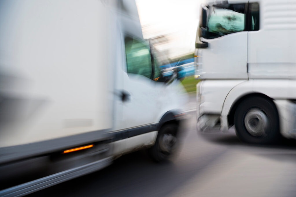 Blurry motion image of two commercial trucks nearly colliding, illustrating the danger of crashes handled by an Oklahoma city truck accident lawyer.