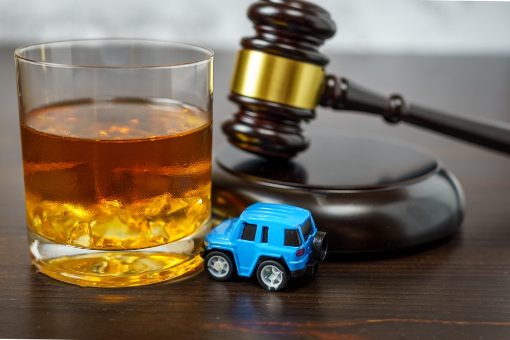 Judge's mace on a table in a court of law, glass of whiskey and miniature car. No drinking while driving concept
