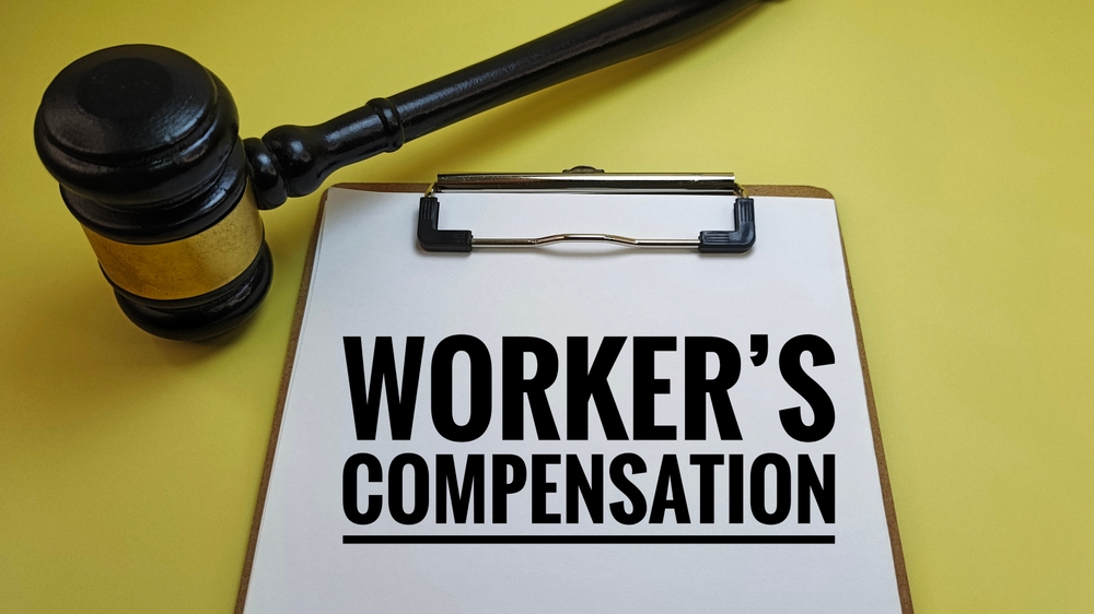 Workers Compensation Text on Clipboard with Judge’s Gavel Representing Workplace Injury Claim, Employee Rights, Legal Protection, or Labor Law Settlement. 
