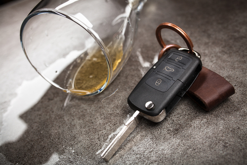 A car key next to a spilled drink on a table, symbolizing drunk driving and the need for an is Kansas City car accident lawyer